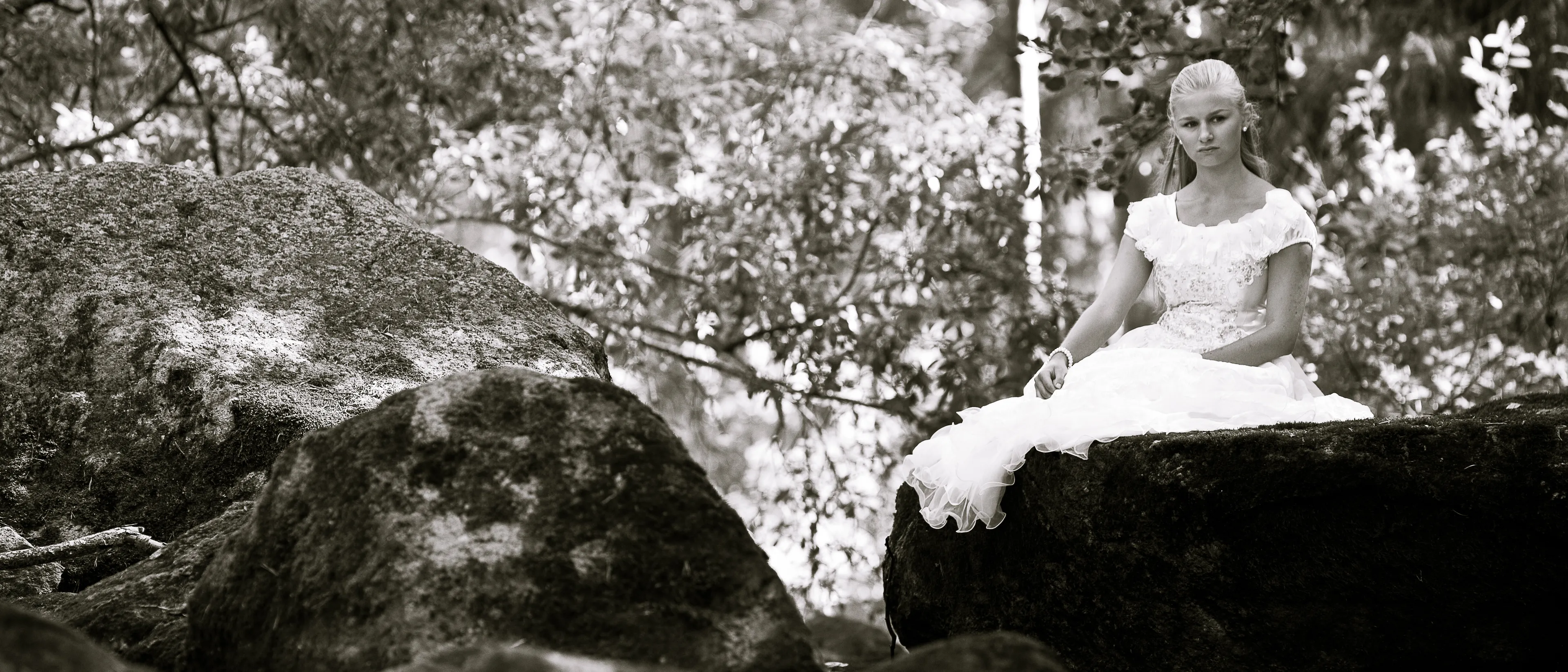 Ruth sitting on a rock in a forest setting