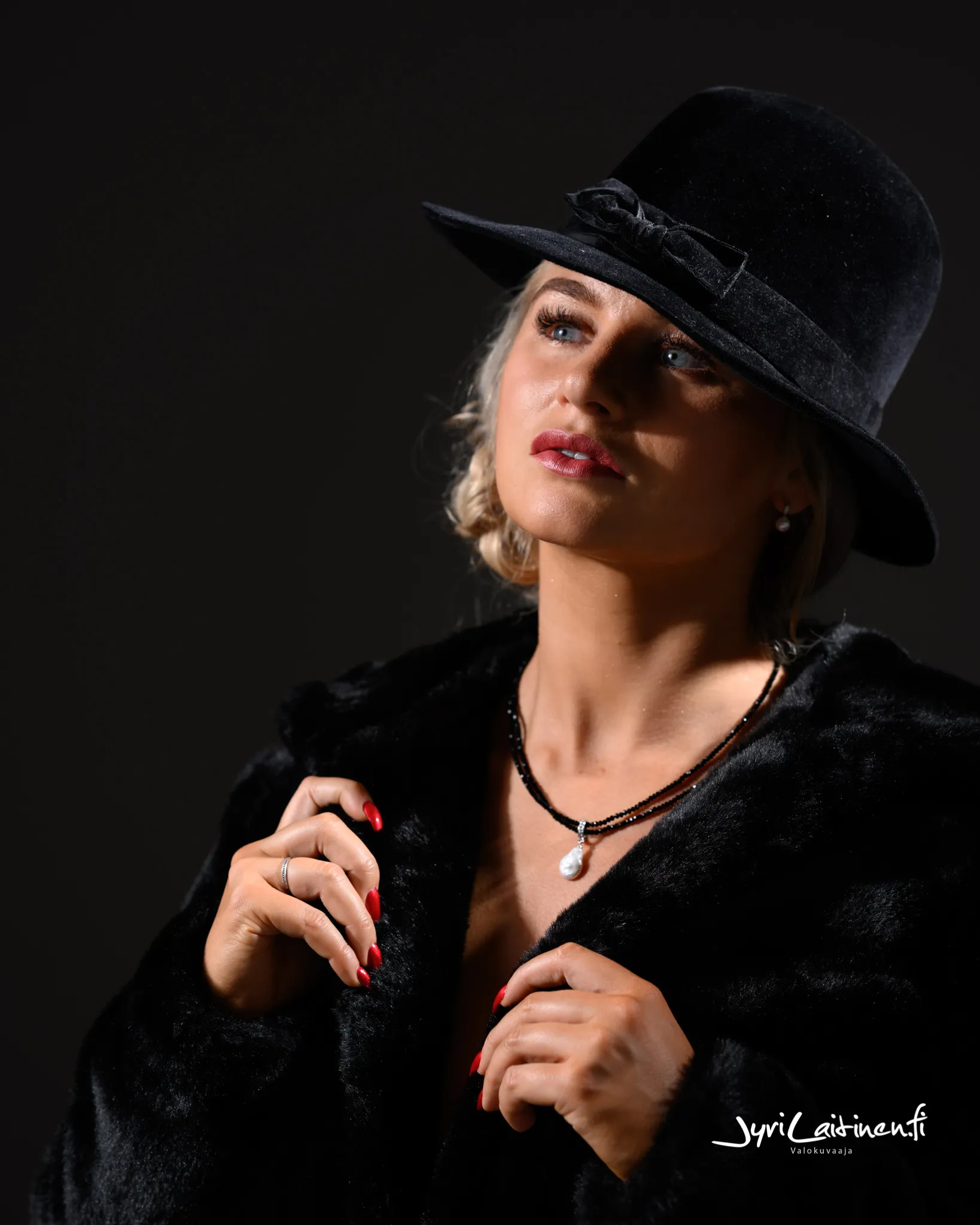 Ruth wearing a hat and fur coat, looking upwards