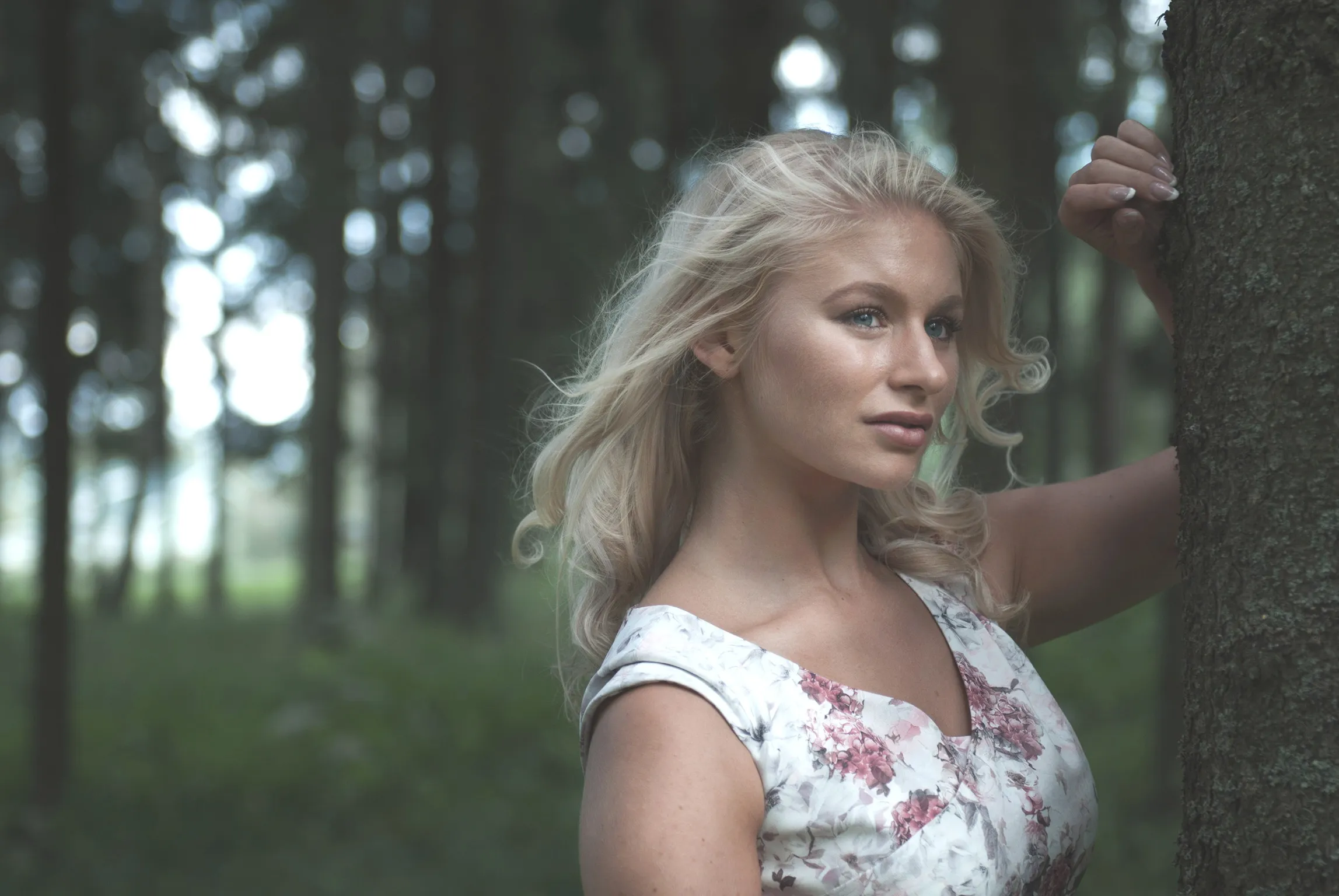 Ruth leaning against tree in forest, floral dress lifestyle