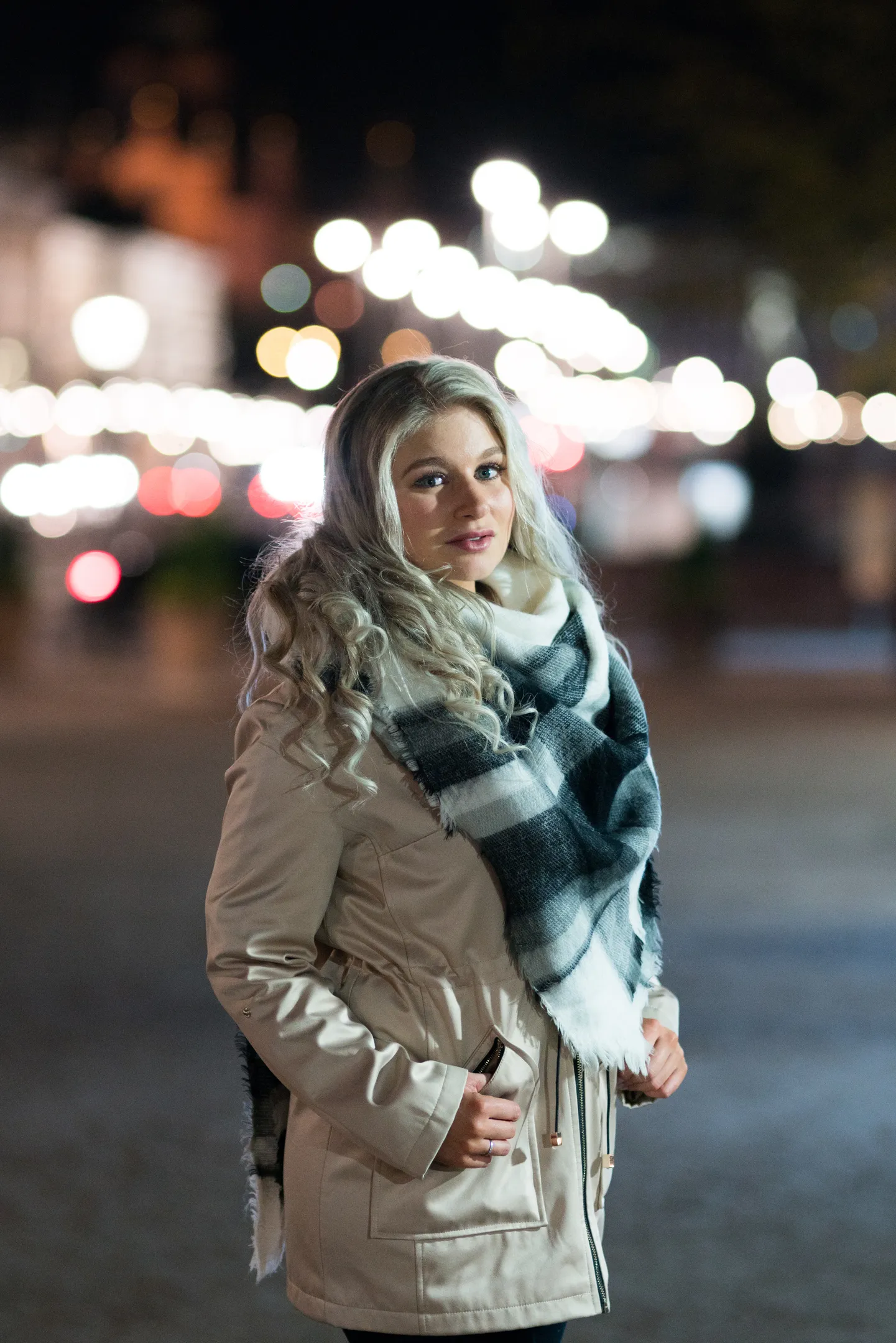 Ruth in winter coat with city lights behind her at night