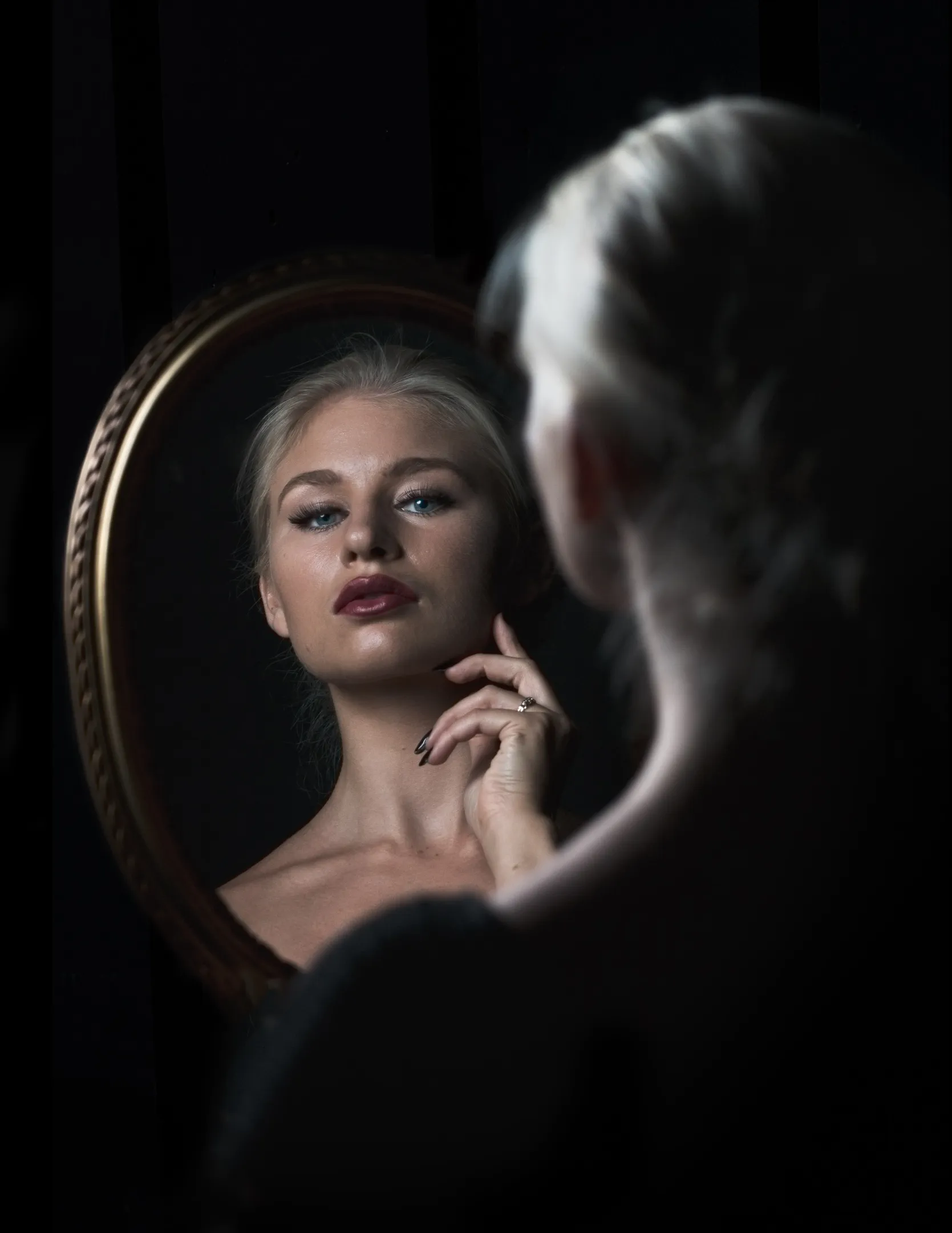 Ruth gazing into ornate mirror in dark cinematic setting