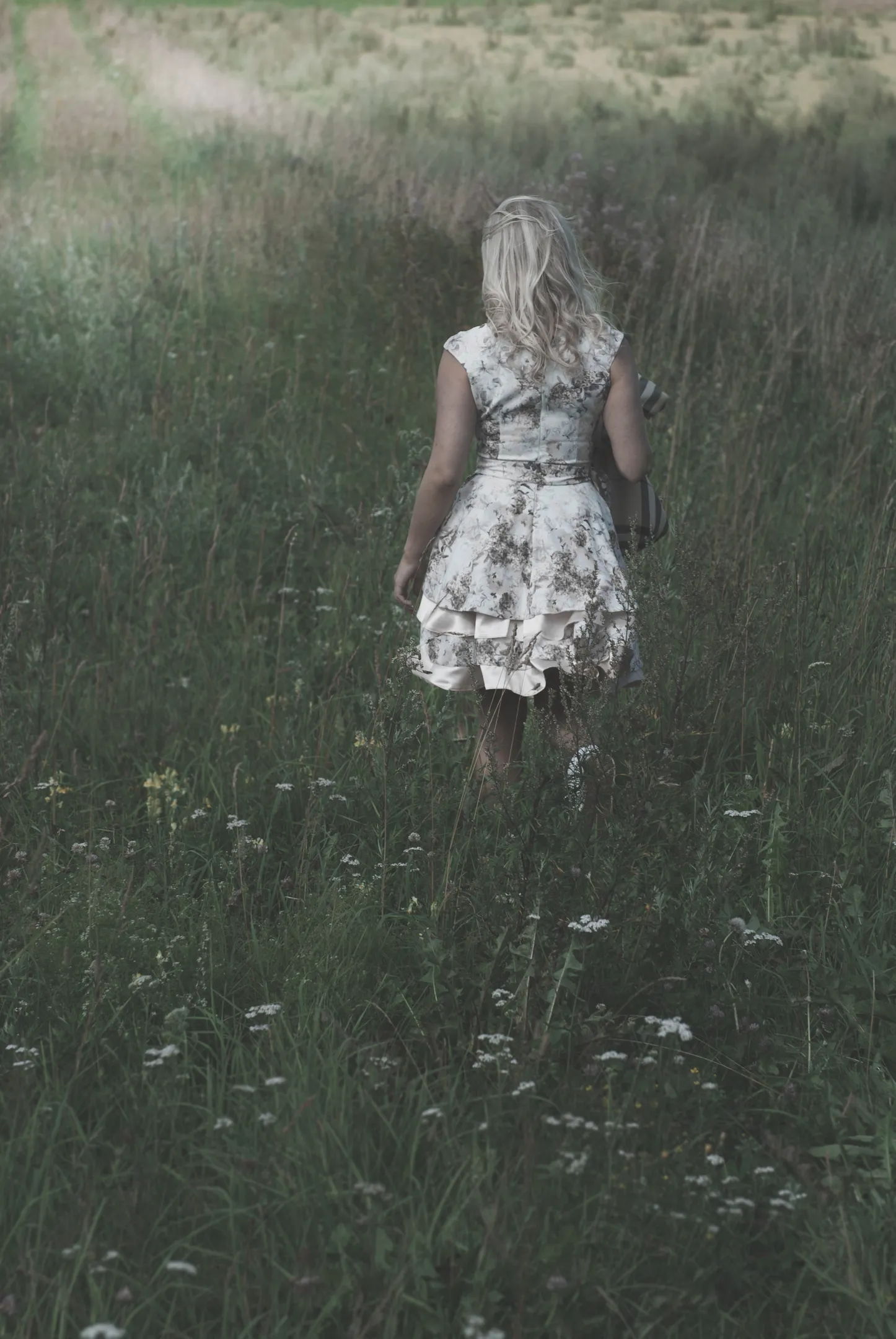Ruth walking away through wildflower meadow in floral dress