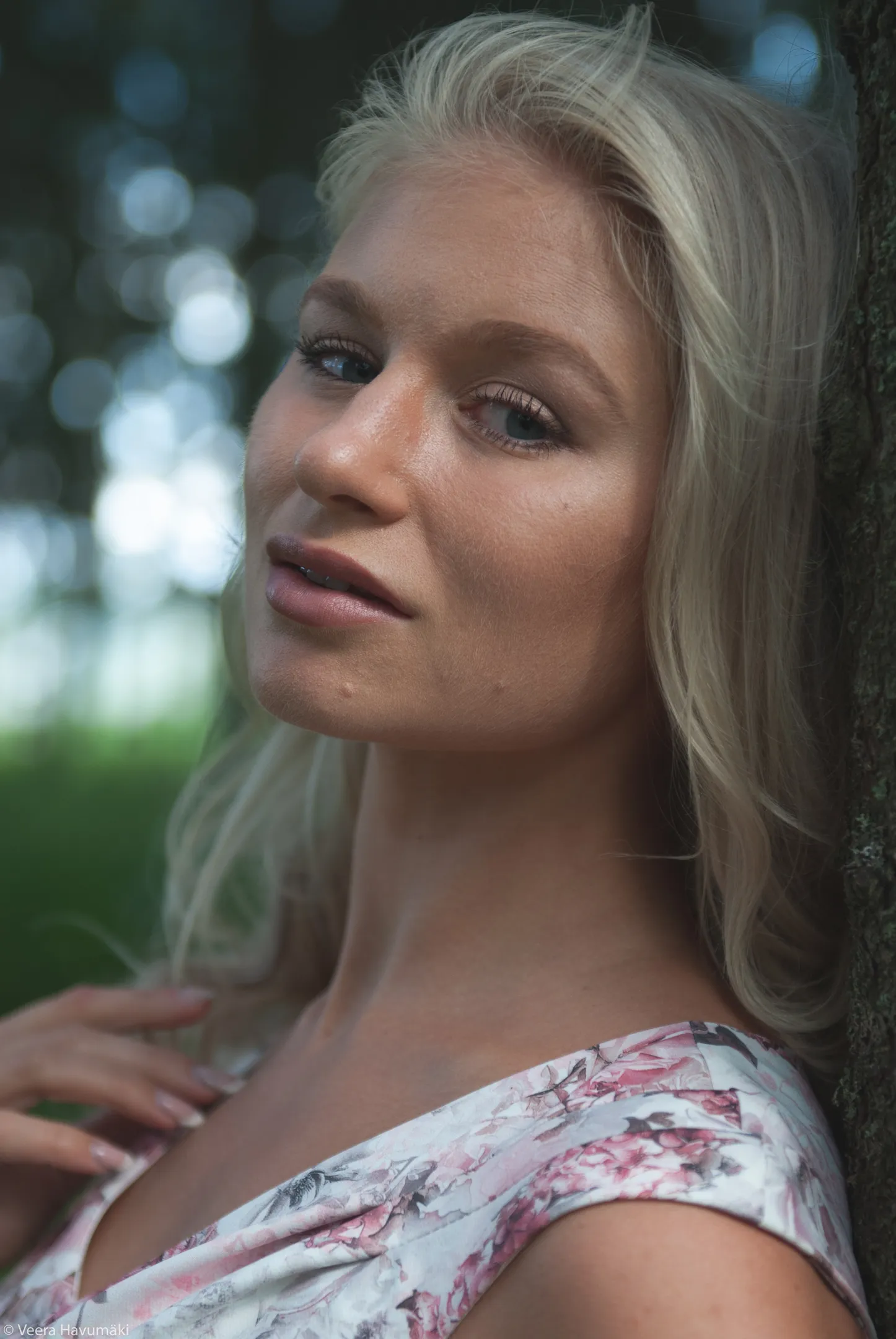 Ruth headshot leaning on tree in floral dress, warm tones