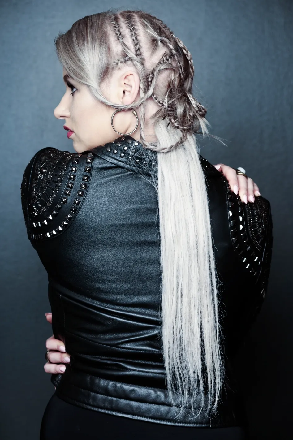 Ruth in studded leather jacket with braided silver hair, from behind