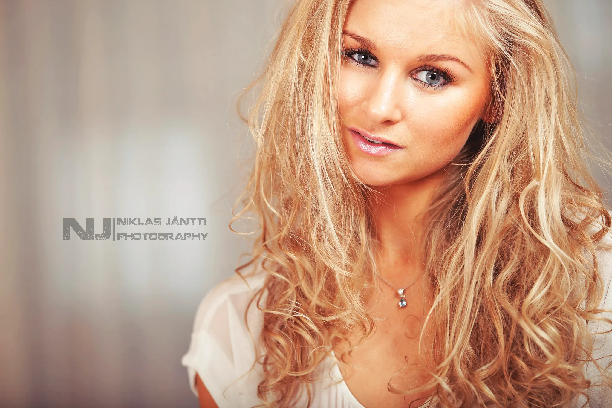 Ruth smiling in warm-toned beauty headshot with curled hair
