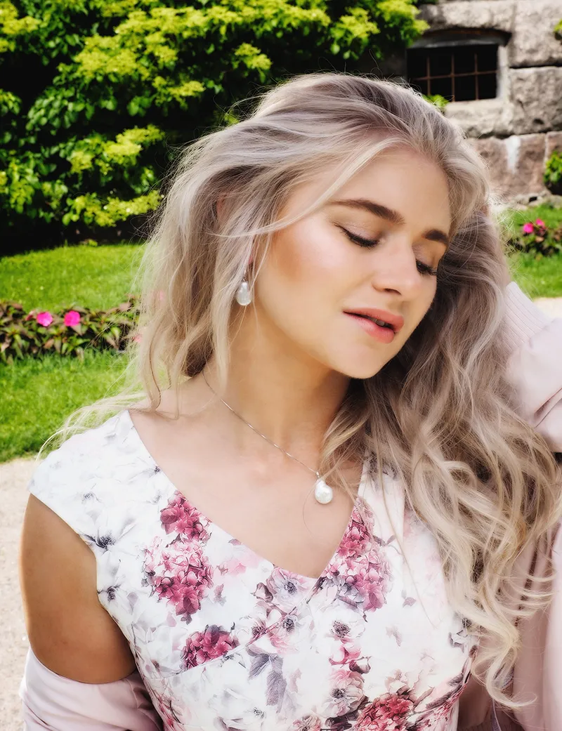 Ruth in garden with eyes closed, floral dress and silver hair
