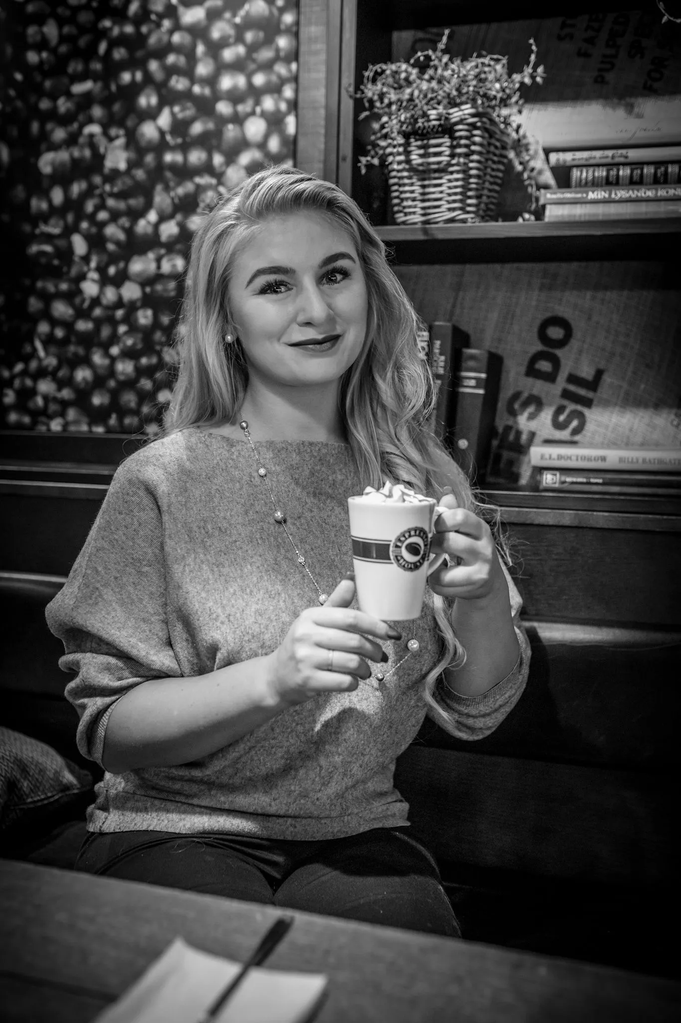 Ruth holding latte at cafe, warm smile in cozy setting