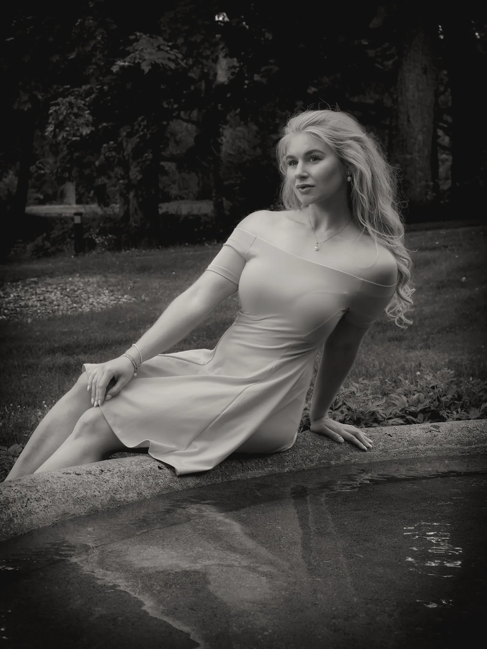 Ruth in black and white seated by water in elegant dress